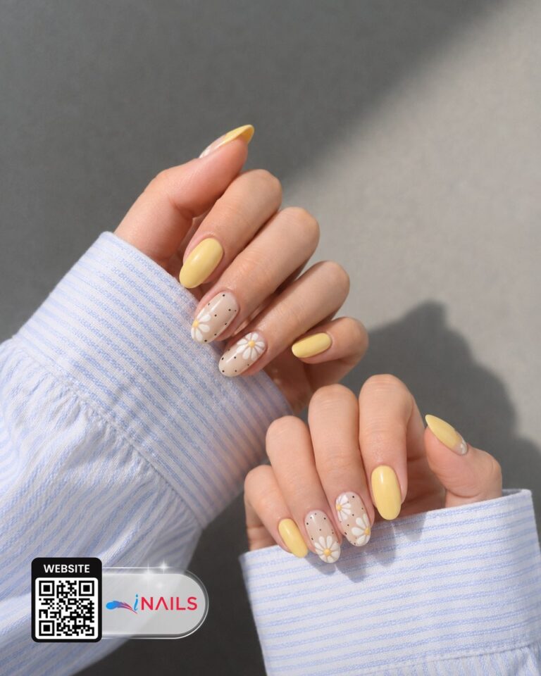 Soft yellow almond nails with delicate white daisy accents at iNAILS in Moncks Corner, SC.
